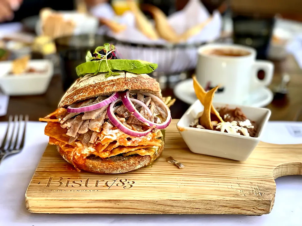Torta de chilaquiles rojos con cecina, cebolla morada y aguacate