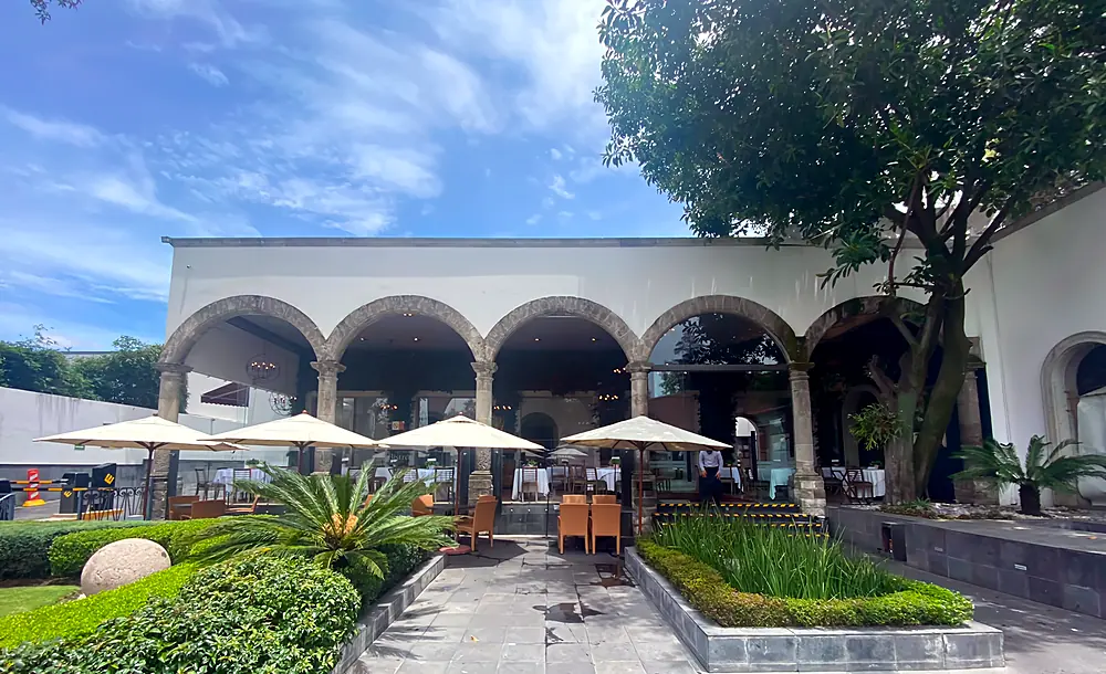 Terraza-jardín de Bistró 83 con arcos, sombrillas y jardín en San Ángel